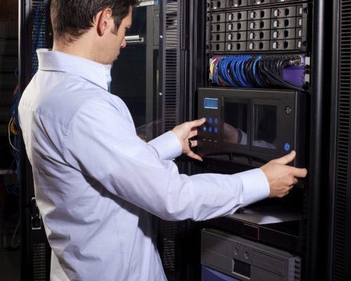 An IT technician adjusting computer equipment in the server room